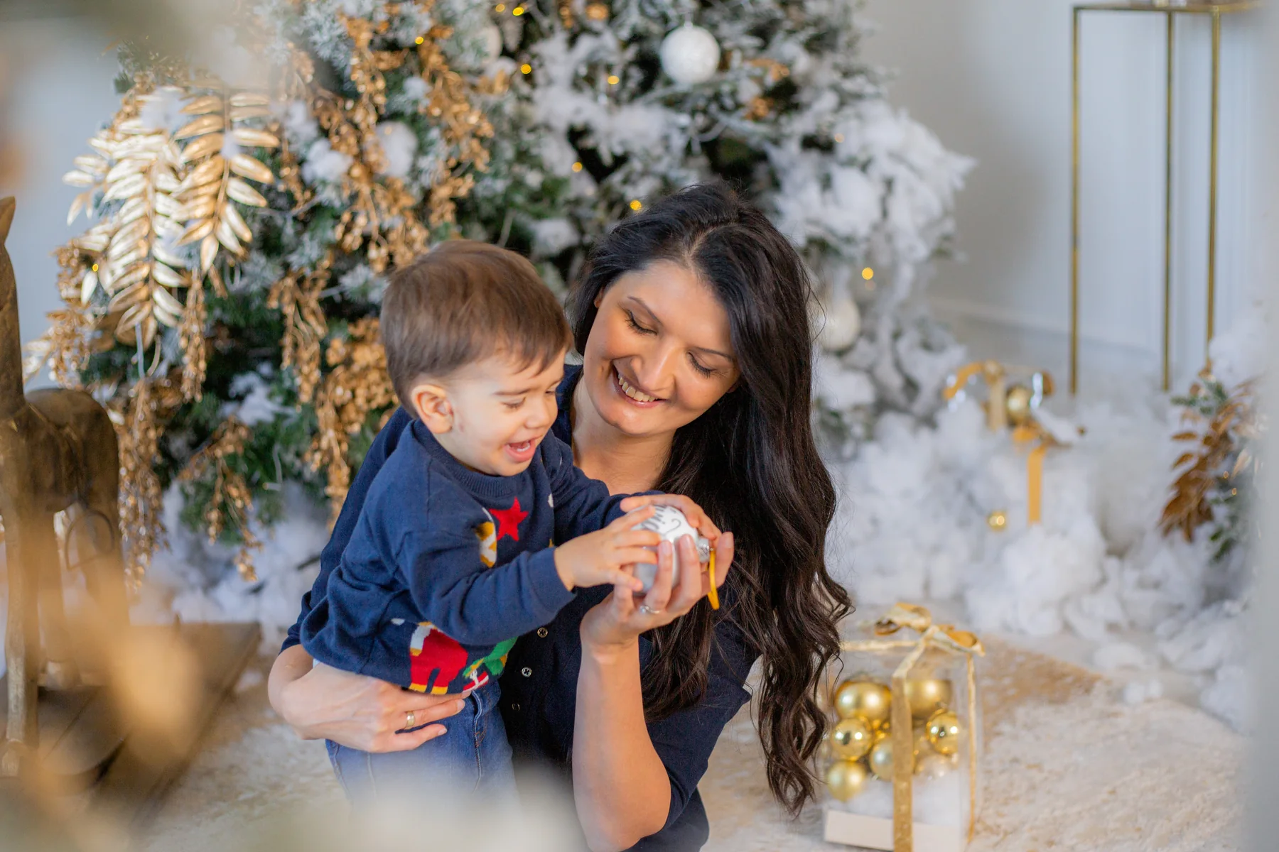Anya és kisfia együtt nevetnek a díszített fenyő előtt